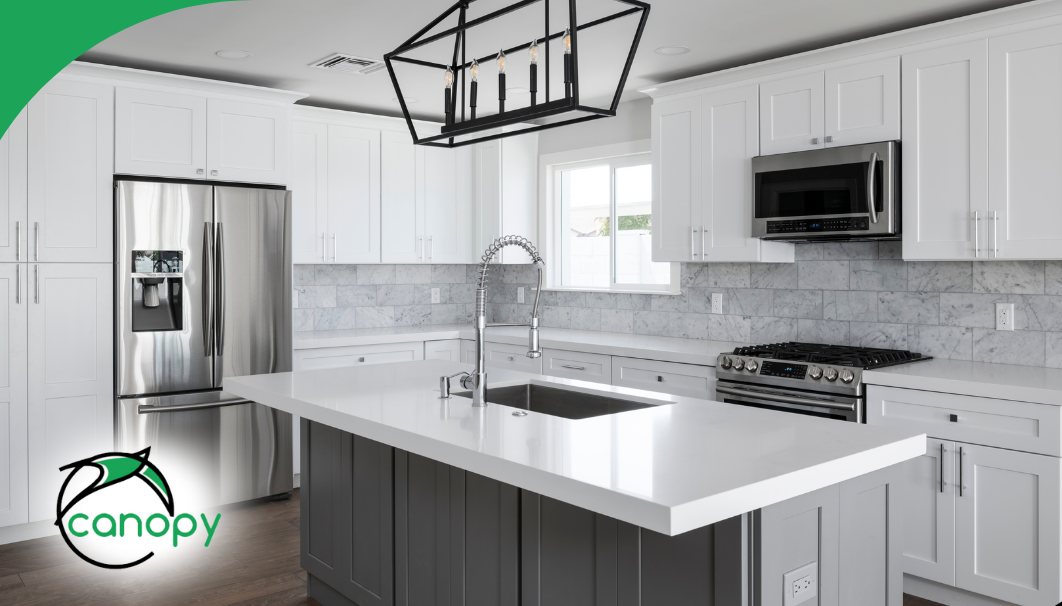 Bright modern kitchen with white cabinetry, gray island, and stainless steel appliances.