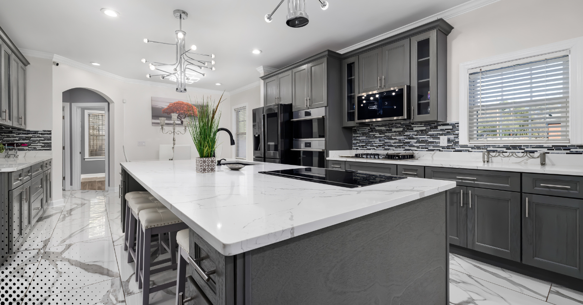 Luxury kitchen with dark gray cabinets, marble countertops, and modern lighting fixtures.