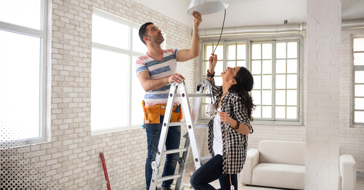 Couple working together to repair ceiling light fixture.