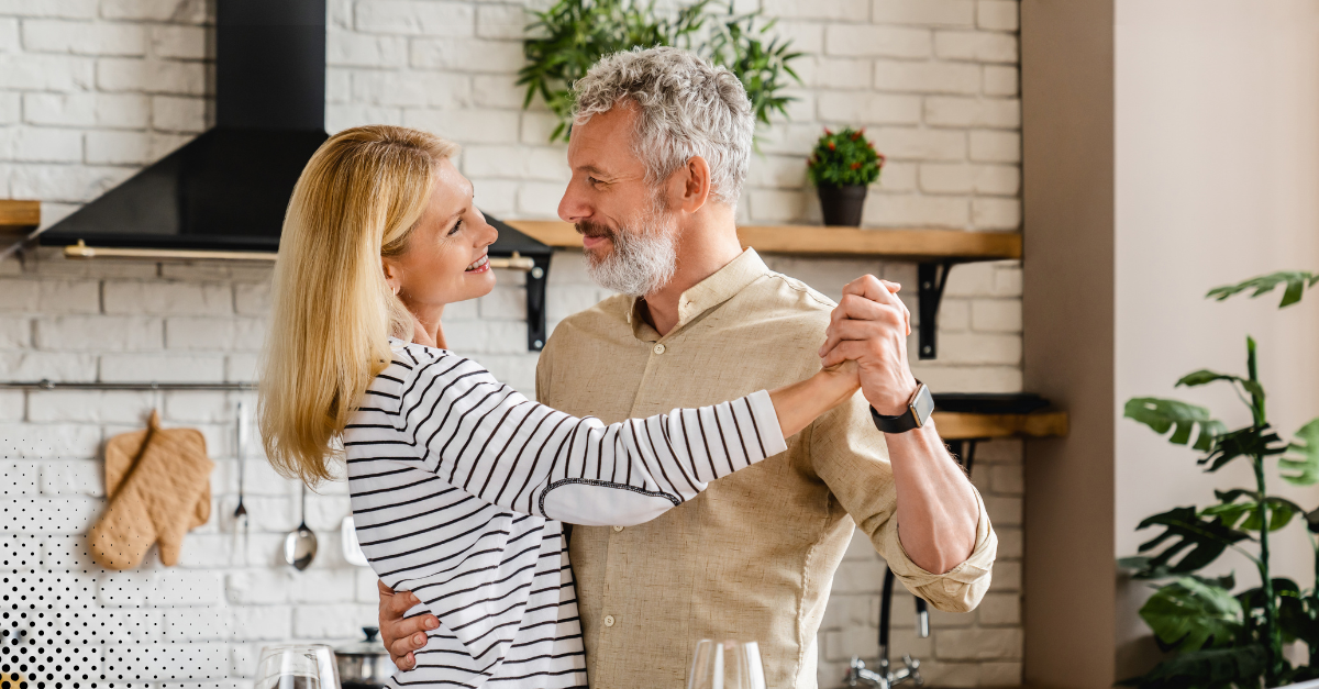 Couple dancing together in their kitchen, sharing a joyful moment.