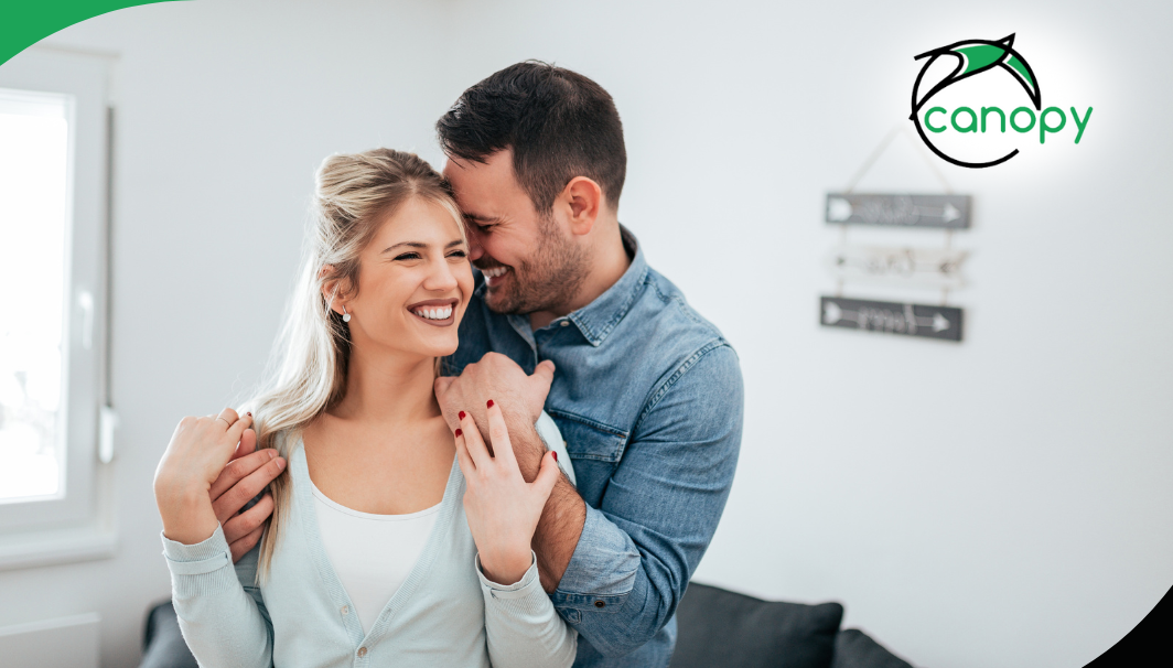 Couple embracing and smiling in their home, enjoying each other’s company.