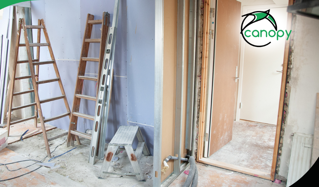 Indoor renovation site with ladders, drywall, and construction materials.