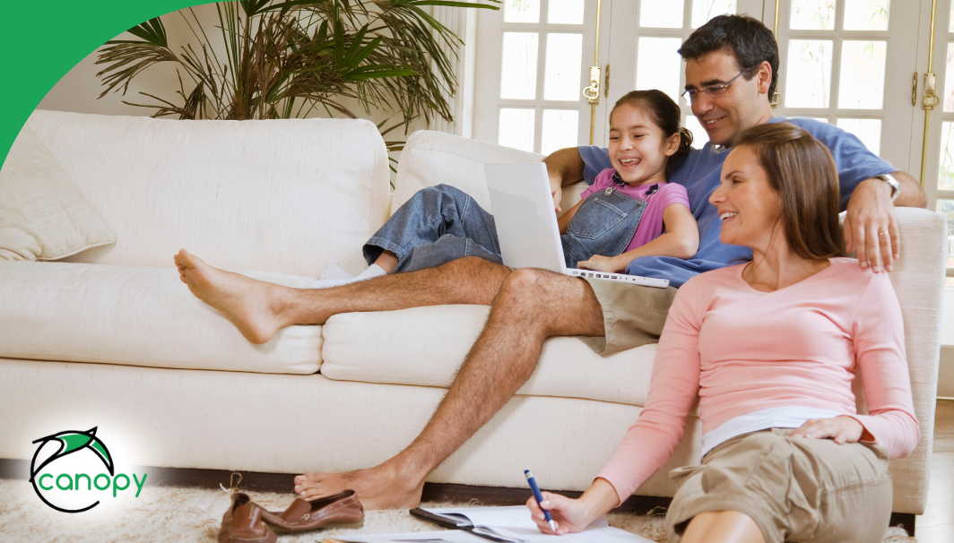 Smiling family relaxing together on the couch with a laptop.